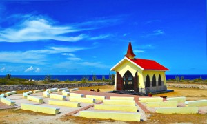 In the picturesque picture, the Alto Vista Church in Aruba stands proudly against a backdrop of serene natural beauty. Nestled amidst Aruba's arid landscape, the church's white façade contrasts beautifully with the vibrant blue sky.