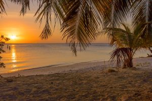 As the sun sets over Surfside Beach in Aruba, the sky transforms into a stunning palette of oranges, pinks, and purples.