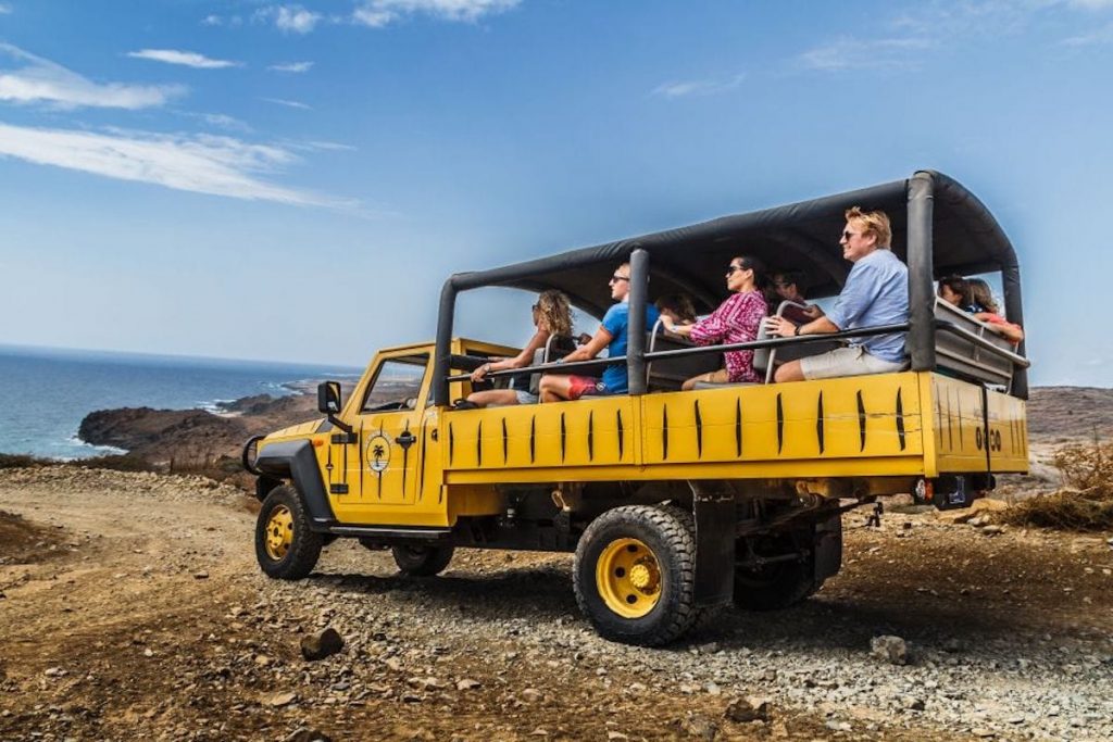 A scene of an exhilarating adventure, exploring the natural pool in Aruba aboard an off-road vehicle. The rugged terrain sets the stage for an exciting journey as the driver navigates through the untamed landscapes of Aruba's east coast.