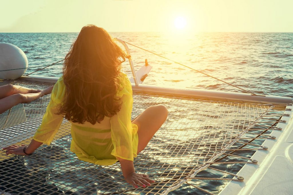 A woman on a catamaran staring at a beautiful sunset
