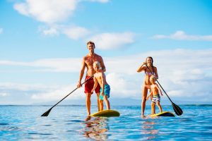 a family with kids enjoying paddle boarding on the calm blue waters in Aruba, Dutch Antilles.