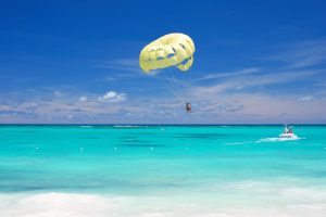 a couple parasailing over the waters of Palm Beach, Aruba.