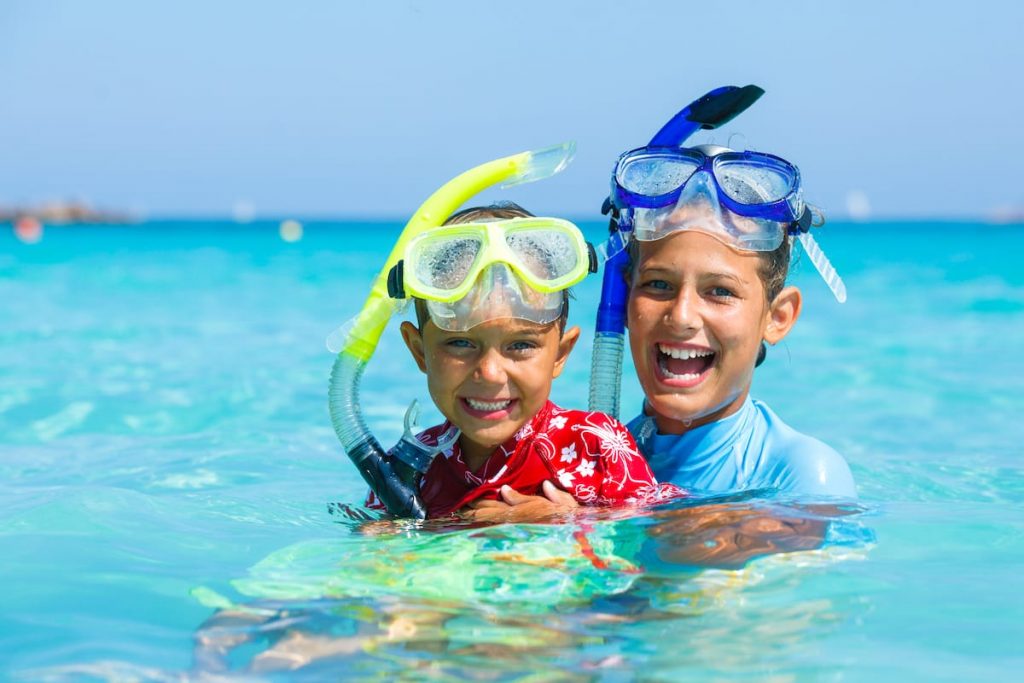 A child is captured experiencing pure joy while snorkeling in the crystal-clear waters of Aruba. The scene is filled with vibrant colors and a sense of adventure.