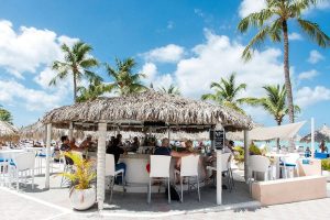 A group of people having a drink at The Beach Bar on Palm Beach, Aruba.