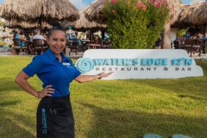 A smiling staff member at the Water's Edge Restaurant & Bar on Eagle Beach, Aruba.