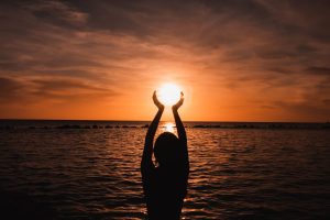 A woman trying to touch the sun during a yoga class in Aruba.